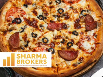 A pizza topped with pepperoni, tomatoes, mushrooms, and black olives, featuring the SHARMA BROKERS logo